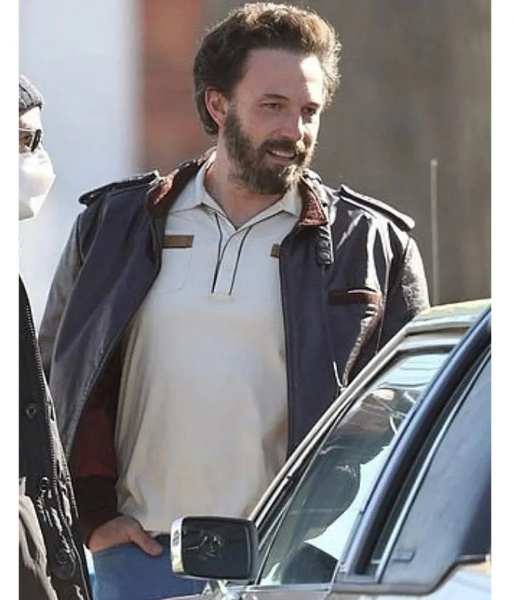 Man standing next to a car wearing a white shirt and dark jacket.